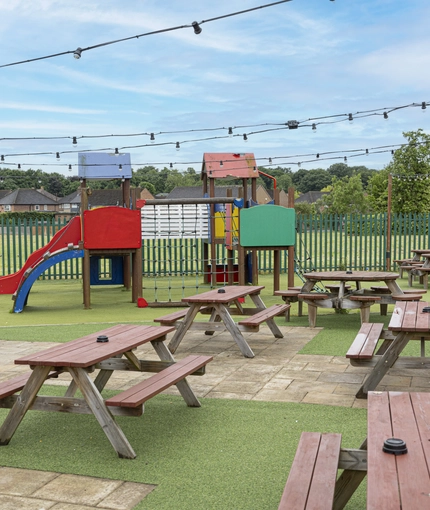 Exterior play area and beer garden of a pub with a seating area.