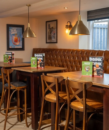 An interior restaurant seating area at The Cherry Tree; with a long, upholstered booth seat against the window, and a TV on the wall.