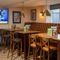 An interior restaurant seating area at The Cherry Tree; with a long, upholstered booth seat against the window, and a TV on the wall.