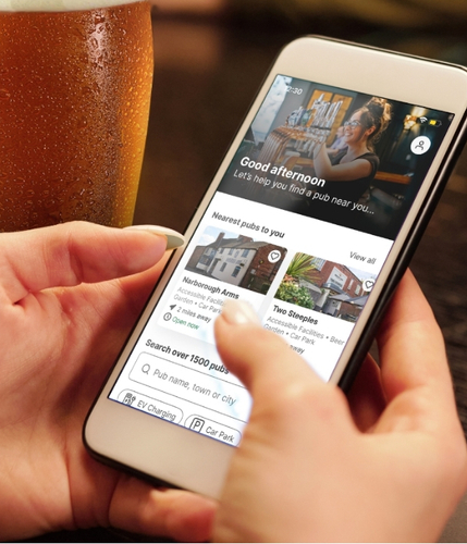 A phone with the Greene King app on it, being held by a person's hands.