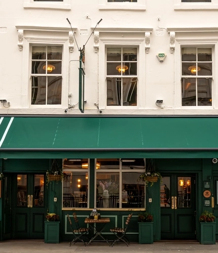 The exterior facade and seating area at the Lord Raglan in Holborn, with an awning over the tables and chairs.