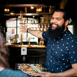 A man greeting people in a pub.