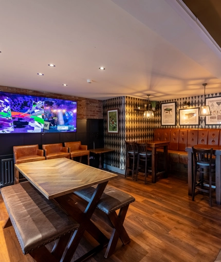 Interior dining area of a pub with a TV and a dartboard.