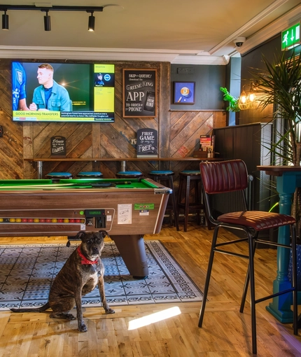 The interior pub games and seating area with TV, dartboard, pool table and electronic pub games at The Hare & Hounds.