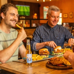 A group of customers sat in the interior restaurant and seating area at a Flaming Grill venue with meals and drinks for Fathers Day.