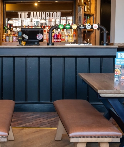 The bar and interior restaurant seating area of The Amington in Tamworth, with upholstered bench seating, and a gaming machine.
