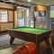 Interior seating area of a pub with a TV, a fireplace, a pool table and a dartboard.