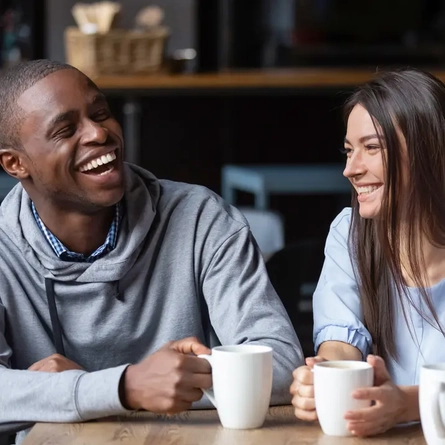A group of people laughing while drinking coffee.
