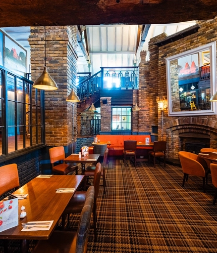 Interior dining area of a pub with a fireplace.