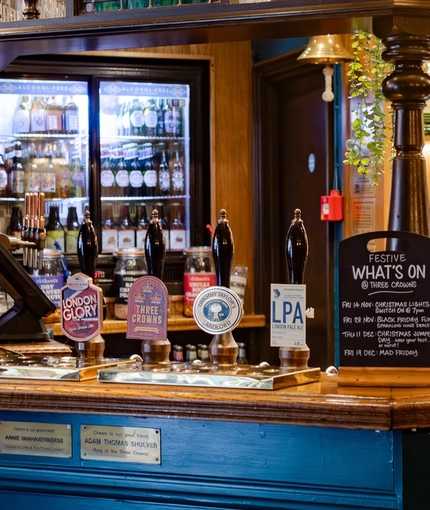The interior bar with advertising signage including a What's On chalkboard at The Three Crowns.