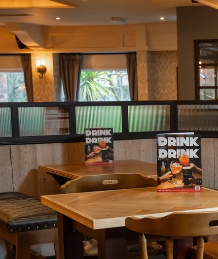 An interior restaurant seating area at the Cuckoo Oak, with upholstered chairs, and a dartboard on the wall.