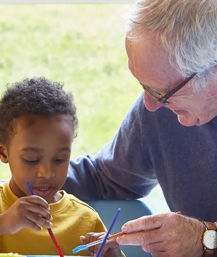A grandad and a grandchild painting together
