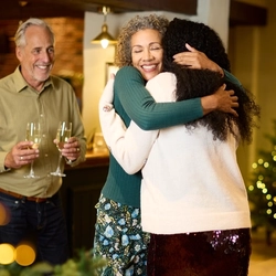 An image of 2 people greeting each other with 1 person standing behind holding drinks within the interior of a Chef & Brewer venue.