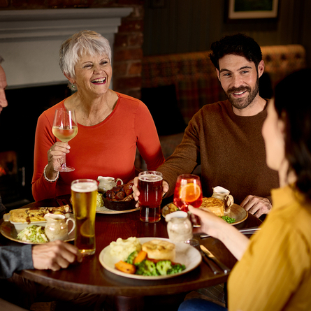An image of 4 customers enjoying mains dishes and various drinks within the interior restaurant and seating area at a Chef & Brewer venue.