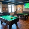 The interior games area at The Victoria in Lytham St Annes, with two pool tables, a TV on the wall, and a dartboard in the corner.