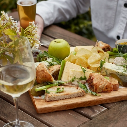 An exterior shot of people enjoying food served in a beer garden at a Chef & Brewer venue.