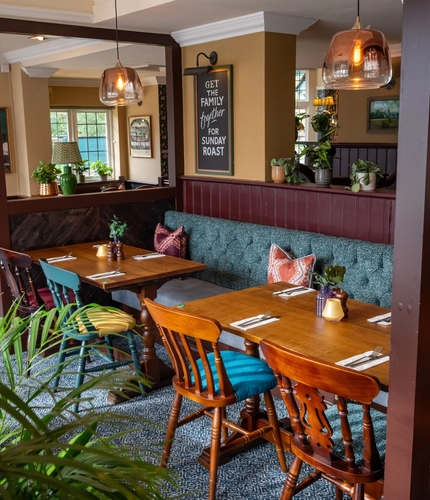 The interior restaurant seating area with tables, chairs, cushioned seating and hanging pendant lighting at The Church View Inn.