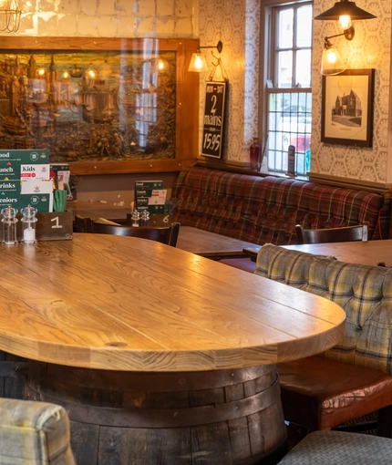 An interior restaurant seating area at The Woolpack Inn; with an upholstered booth seat, and a large TV on the wall.