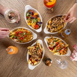 Small plates of loaded fries with hands in the image