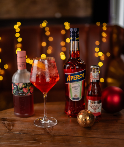 a glass of wine and a few bottles sitting on a wooden table of a pub