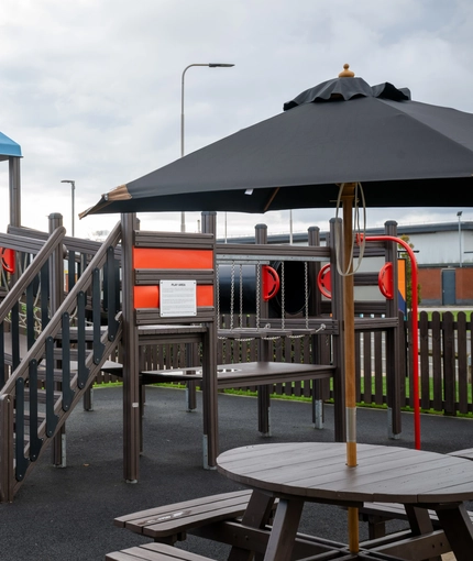 The exterior children's play area at The Parsonage in Leigh, with a picnic table and shade umbrella.