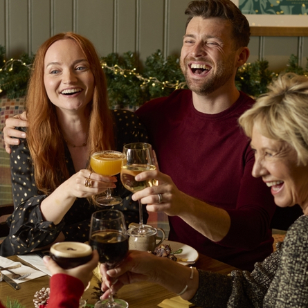 A banner showing a group of people sat at a table enjoying Festive Drinks within the interior seating area at a Chef & Brewer venue.