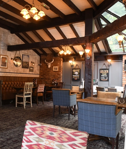 Interior conservatory of a pub with a dining area and a TV.