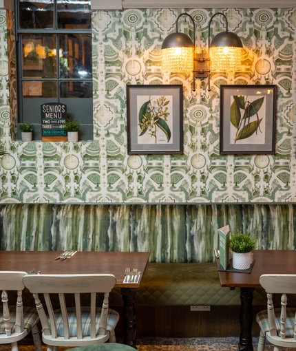 Two tables in the restaurant of The Rockingham Arms, next to a plant.