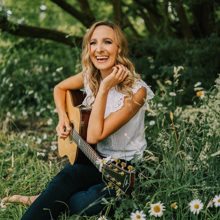 A image of a performer outside posing for the camera holding a guitar, used to advertise 'whats on' in Crafted venues.