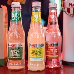 two bottles of lemonade and a bottle of gin sitting on a bar counter
