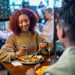 An image of a couple enjoying food and drinks within the interior restaurant seating area at a Community Pubs With Food venue.