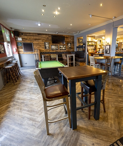 Interior dining area of a pub with a pool table, a TV and a gambling machine.