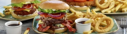 Three plates of burger, chips and onion rings