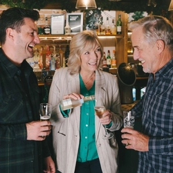 A group of friends stood round the bar with low and no drinks in a Greene King venue.