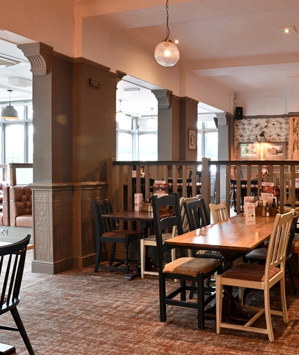 Interior dining area of a pub with a TV playing tennis.