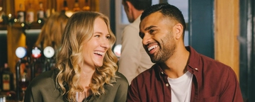 An image of 2 friends sat within the interior seating area enjoying various drinks.