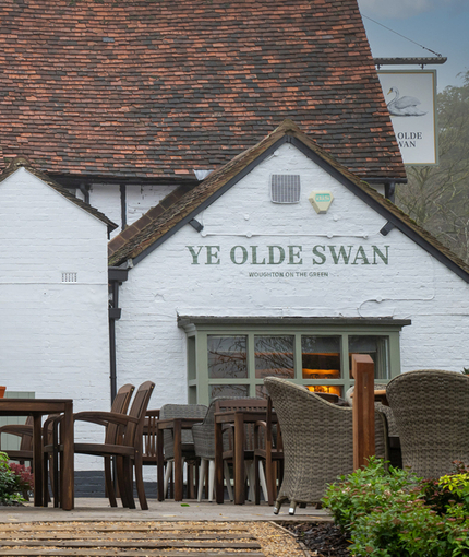 The exterior facade, signage, and beer garden seating area of Ye Olde Swan.