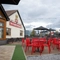 The exterior beer garden seating area at The Parsonage in Leigh, with string lights overhead and shade umbrellas at some of the tables.