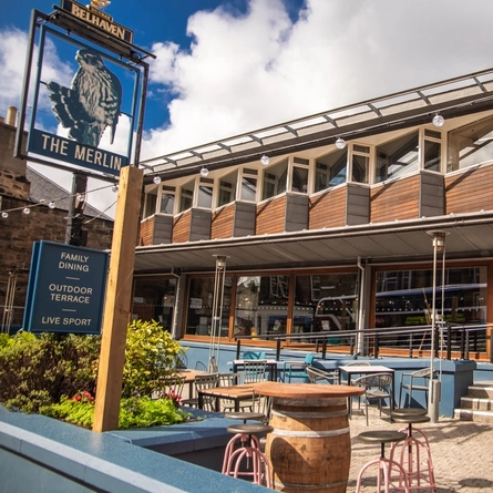 The exterior facade, signage and beer garden seating area of The Merlin in Edinburgh.