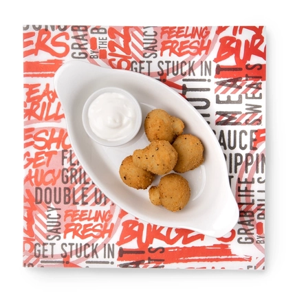 A top-down view of five breaded garlic mushrooms served in a roasting dish with a small pot of dipping sauce.