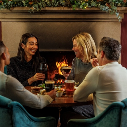 An image of people enjoying various festive snacks and drinks within the interior restaurant seating area during Christmas time at The Watermill.