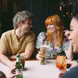 A group of friends sat around a table in the seating area of a Greene King venue enjoying drinks on a £3 deal.