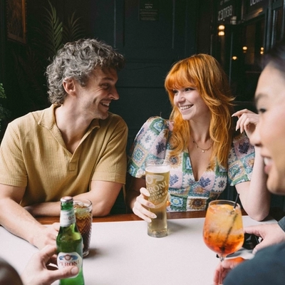 A group of friends sat around a table in the seating area of a Greene King venue enjoying drinks on a £3 deal.