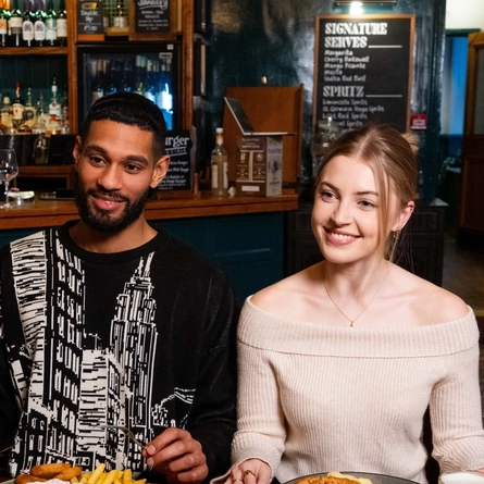 A group of friends sat in the interior restaurant and seating area in a Urban Social venue, enjoying main meals and drinks.