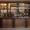 A close up view of the bar at The Man On The Moon, showing the beer taps, bottles of various wines and spirits on shelves, and glasses hanging in racks above the bar.