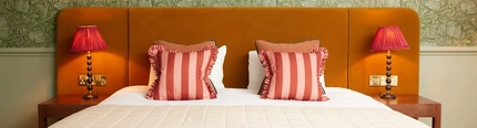 A double hotel room bed with cushions, bed side tables and lamps at The Dog and Partridge.