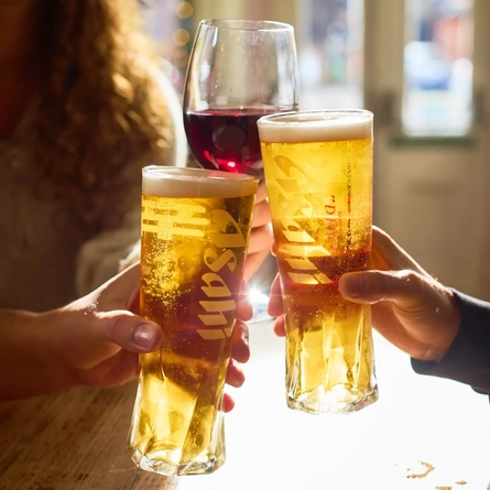 A lifestyle image of 3 customers enjoying drinks sat at a table and celebrating with a cheers within the interior seating area at a Metro venue.
