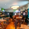 The bar and interior restaurant seating area at the Royal George; with wooden flooring, an upholstered booth seat, and TVs on the walls.