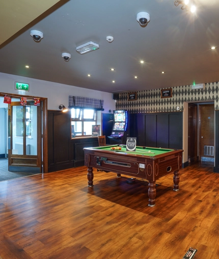 Interior dining area of a pub with a pool table, a gambling machine and a TV.