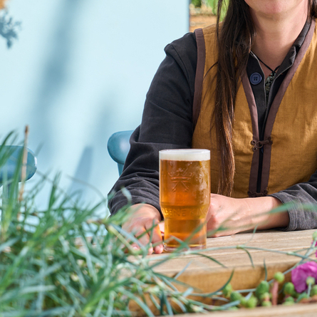 A woman sitting at a beer garden table with a pint of beer.